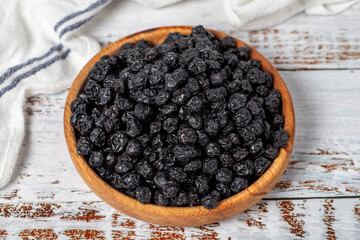 Natural dried blueberry grains in bowl on wooden background. Fruit snack for a health diet and alternative desert. Close up
