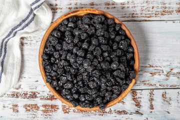 Natural dried blueberry grains in bowl on wooden background. Fruit snack for a health diet and...