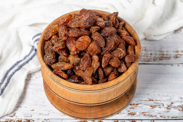 Natural dried grapes in bowl on wooden background. Fruit snack for a health diet and alternative desert. Close up