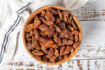 Natural dried grapes in bowl on wooden background. Fruit snack for a health diet and alternative desert. Top view