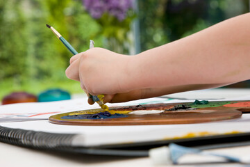 Young girl hands squeezing oil color tube
