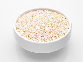 Close-up white sesame seeds in a white round deep bowl on a white background. Healthy food. Selective focus.