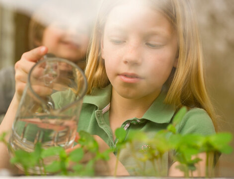 Girl watering seedlings with jug

