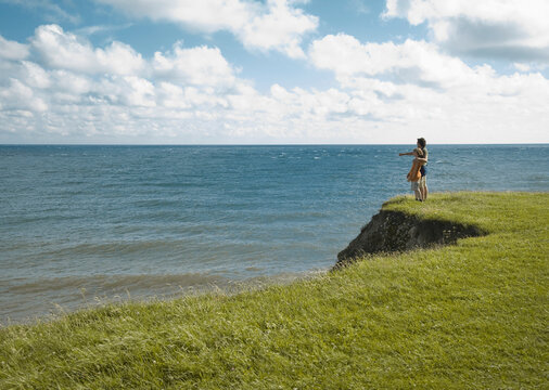 Father and son standing on the edge of a cliff admiring the ocean

