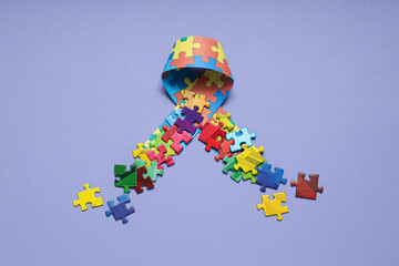 Ribbon with multi-colored puzzle pieces on a light background. World autism day concept