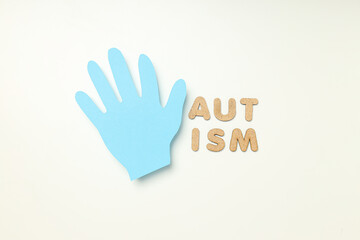 Light blue paper hand with word 'autism' on white background. World autism day concept