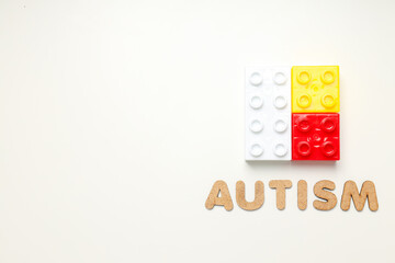 The word autism in wooden letters on a light background with blockss, place for text. World autism day concept