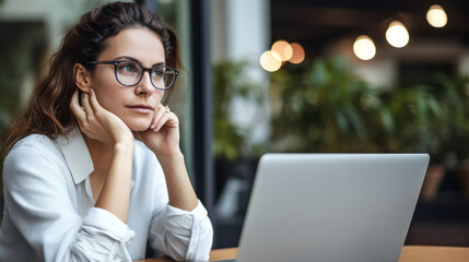 Pensive professional woman thinking at work in front of her laptop computer