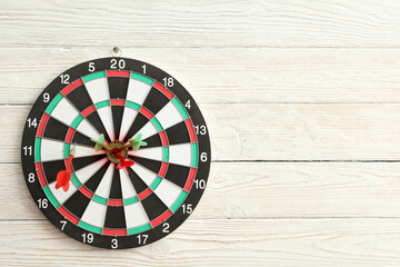 Dart board with wires in the target, on a light wooden background