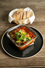 Shakshuka with homemade bread on wooden table