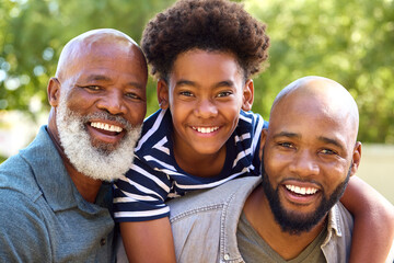 Portrait Of Multi-Generation Male Family Having Fun Playing Outdoors In Garden Park Or Countryside