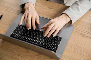 cropped view of middle aged businesswoman typing on laptop in modern office, top view