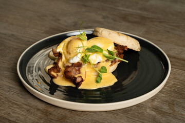 Eggs Benedict with bacon and ham on a wooden table