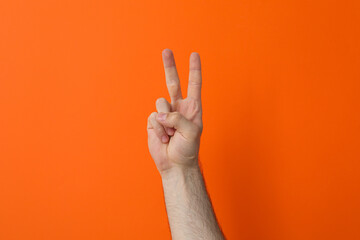 Naklejka premium Female hand showing two fingers on a orange background