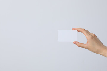 White blank sheet of paper in the hands of a woman on a light background, place for text