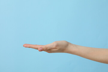 Female hand outstretched on light blue background