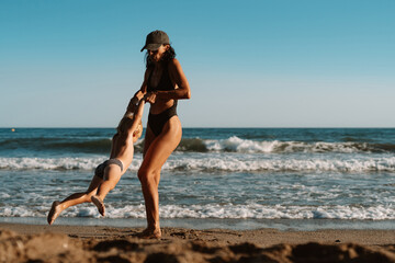 Fototapeta na wymiar beautiful sports mom runs with her son along the seashore on the beach