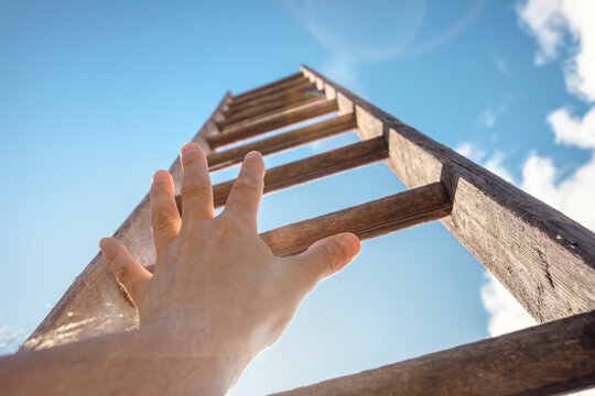 Hand reaching for ladder of success