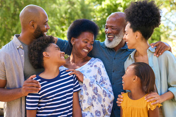 Portrait Of Multi-Generation Family Standing Outdoors In Garden Or Countryside Smiling At Camera