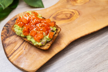 Homemade toast sandwich with salmon, avocado and spices on cutting board. Healthy Breakfast, Dieting, gluten-free bread, guacamole.
