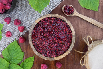 Wooden bowl of with homemade raspberry jam, fresh ingredients on wooden background. Top view, flat lay.