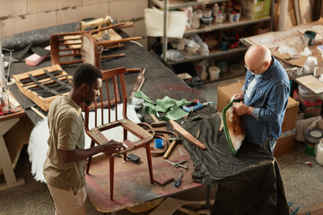 Top view at two people refurbishing vintage furniture in rustic workshop, copy space