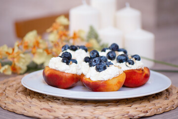 Grilled peach with cream cheese, blueberry and pine nuts on white plate