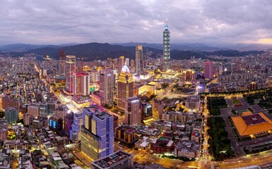 Aerial skyline of Downtown Taipei at dusk, vibrant capital city of Taiwan, with 101 Tower standing out amid skyscrapers in Xinyi Commercial District and oval shaped Taipei Dome located in nearby area