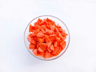 Slices of raw carrots in a glass bowl on a white background. vegetables. cooking preparation. healthy living. Top view
