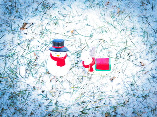 雪の積もった芝生の上の雪だるまとトナカイの玩具