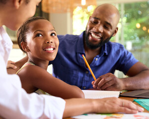 Family Around Table At Home Using Laptop With Parents Helping Daughter With Homework © Monkey Business
