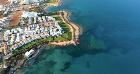 Schilderijen op glas Drone shooting panorama of the coastline of the city with luxury hotels, villas, bays, ports with stylish yachts, sandy and rocky beaches and calm sea with clear blue water in Larnaca Cyprus © Anton
