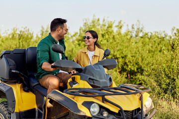 Fototapeta na wymiar A smiling woman stands outdoors beside her boyfriend on a rental quad bike.