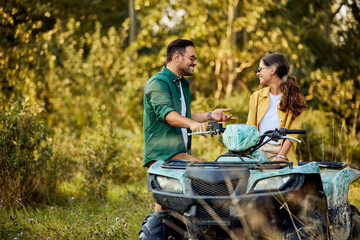 A smiling love couple parked a rented quad bike in nature and talked.