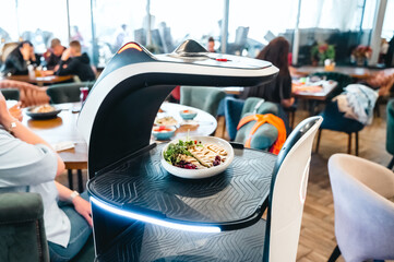Robot waiter serve food at modern restaurant table.Offering innovation futuristic high-tech automated dining experience.Bringing,delivery automation order to customer.Digital robotic AI smart service