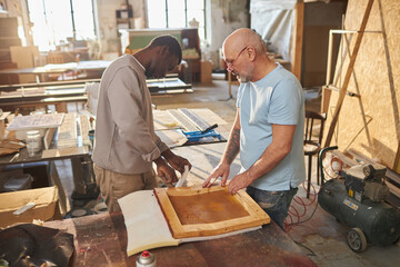 Portrait of two carpenters working together building wooden furniture in workshop, copy space