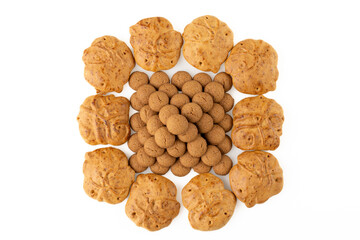 Kruidnoten are crunchy biscuits with gingerbread spices, which are often eaten during the Sinterklaas celebration in the Netherlands. Pyramid of spice nuts wit taai taai on white background.