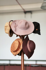 A variety of vintage colorful hats hanging on the wooden brown coat rack