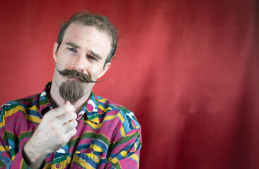 Hipster man with mustache and handsome stroking his chin smug looking at camera