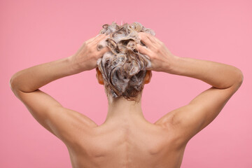 Woman washing hair on pink background, back view