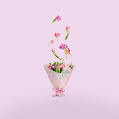 Tulip flowers falling into beautiful bouquet on pink background