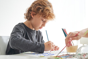 Focused boy painting with paintbrush