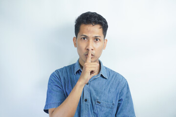 Fototapeta na wymiar Serious good looking male with trendy hairdo, keeps fore finger on lips, tries to keep conspiracy, says: Shh, make silence please. Isolated shot of attractive man shows silence sign