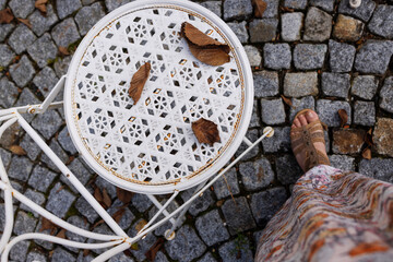Woman in dress near white beautiful chair on the street, top view