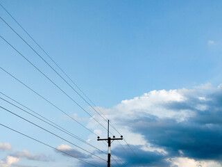 Rural electricity poles against a backdrop of blue sky and clouds.