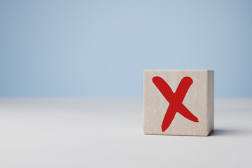Red cross mark, x, wrong mark sign, red cross sign on edge of wooden cube. Concept of negative...