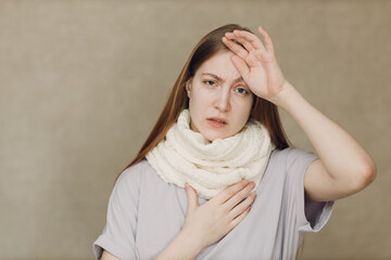 Naklejka premium Young woman wearing scarf holds head flu catarrh ill sick disease treatment cold