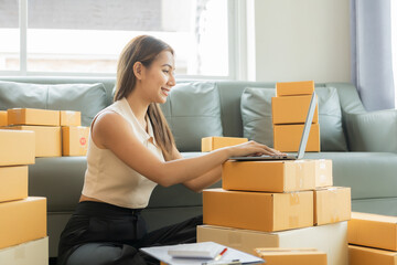A small business entrepreneur, start-up or freelance Asian woman working with parcel boxes and laptops, a successful Asian woman with packaging boxes, her online marketing and shipping.