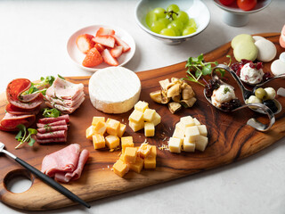 A variety of cube cheese, raw ham, and sweet desserts