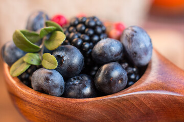 Blackberries, cranberries and blueberries in a wooden cup on the table. Village concept